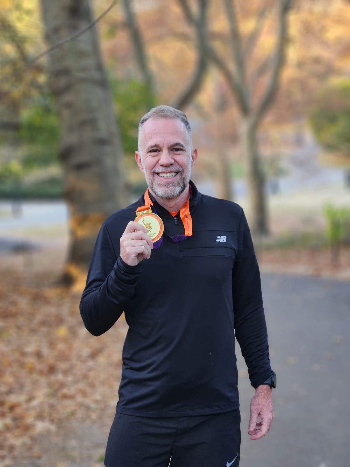 César Aarão celebrando com sua medalha, em um parque